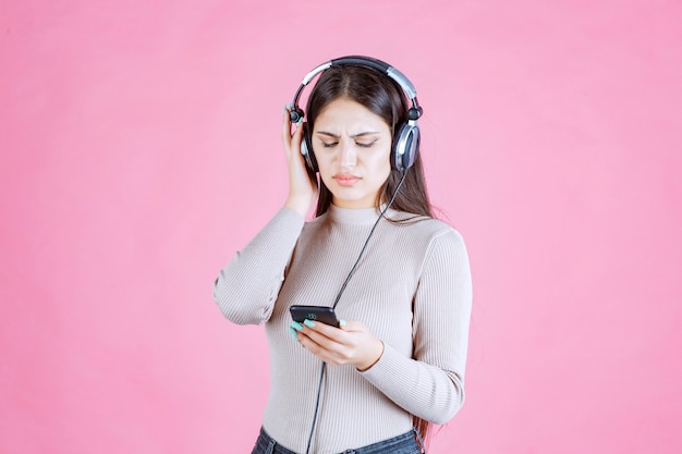 Mulher jovem usando fones de ouvido e não curtindo a música em sua playlist