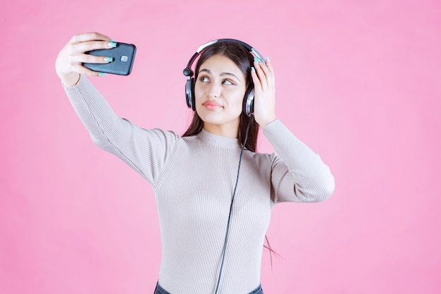 Mulher jovem usando fones de ouvido e tirando uma selfie