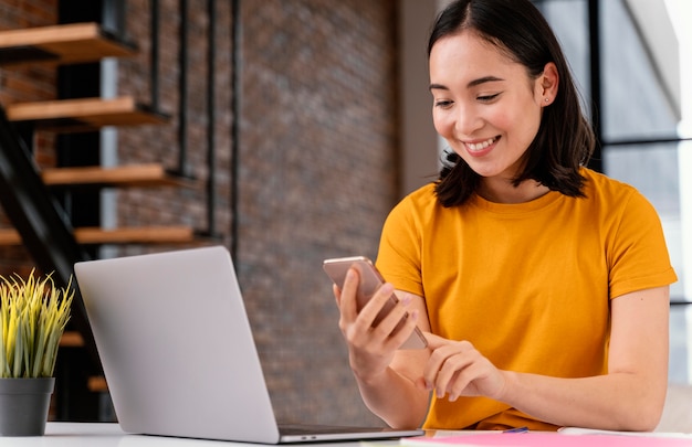 Mulher jovem usando o telefone enquanto participa de uma aula online