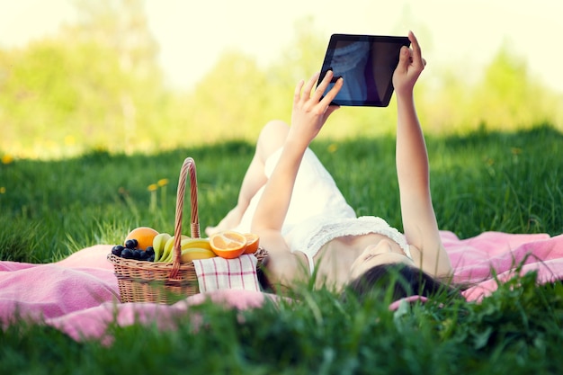 Mulher jovem usando tablet digital no prado