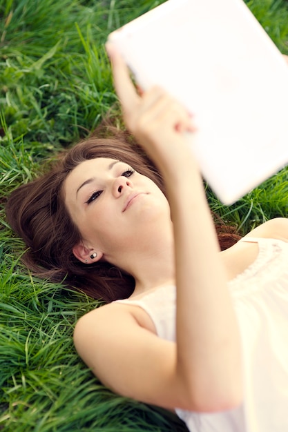Mulher jovem usando tablet digital no prado