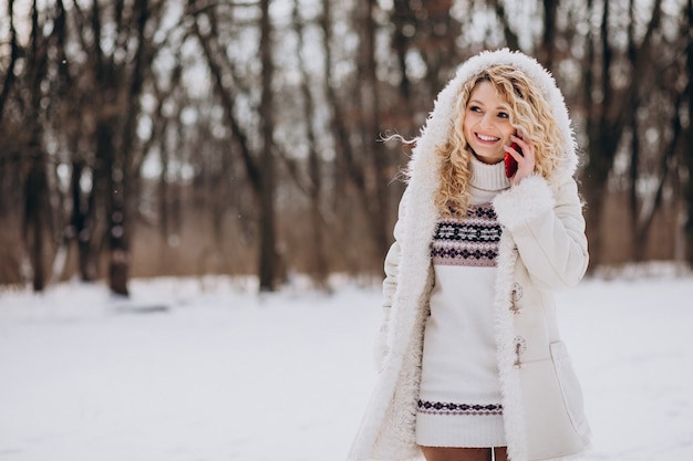 Mulher jovem usando telefone em um parque de inverno