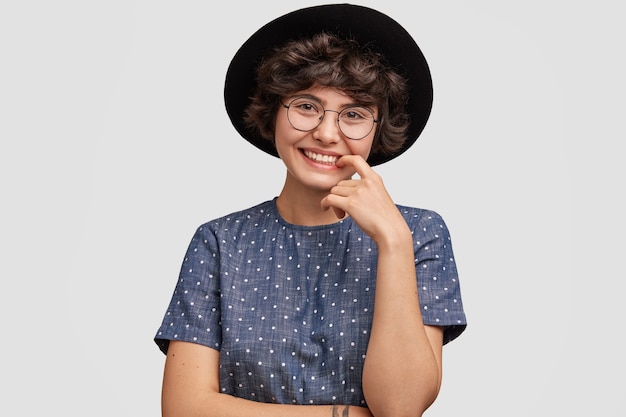 Mulher jovem vestindo blusa de bolinhas e chapéu grande