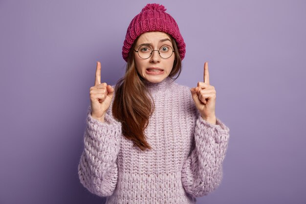 Mulher jovem vestindo um suéter roxo e um chapéu