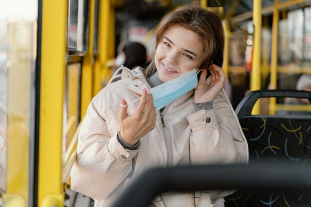 Mulher jovem viajando de ônibus municipal com máscara cirúrgica