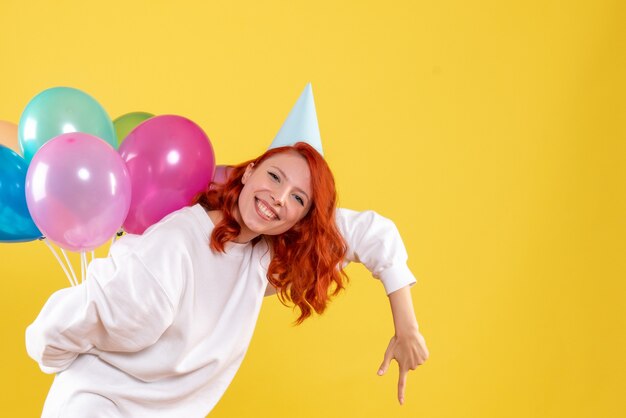 Mulher jovem, vista frontal, escondendo balões coloridos atrás das costas festa de ano novo cor mulher natal