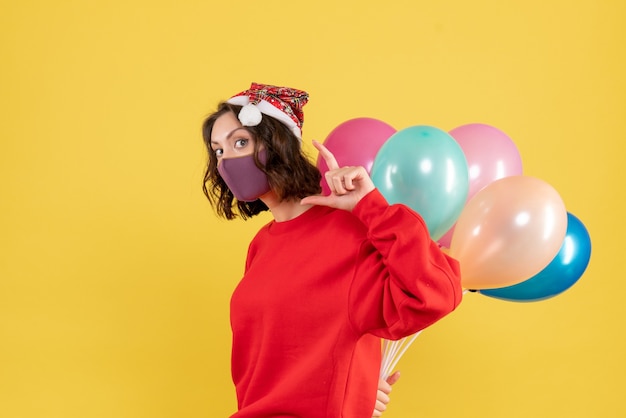 Mulher jovem, vista frontal, escondendo balões em estéril máscara cor férias emoção ano novo natal mulher