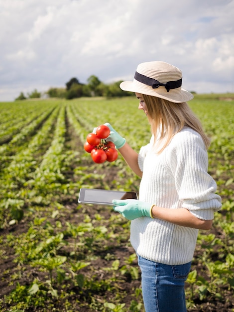 Mulher lateral segurando alguns tomates