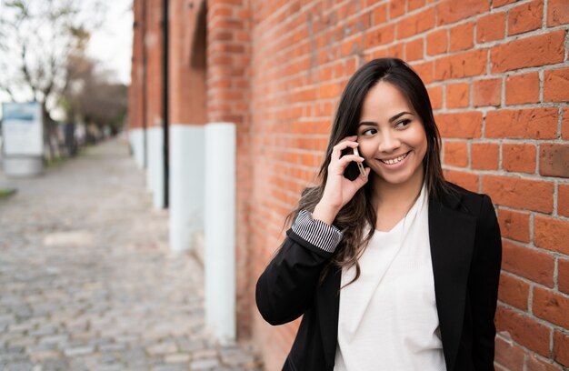 Mulher latina falando ao telefone.