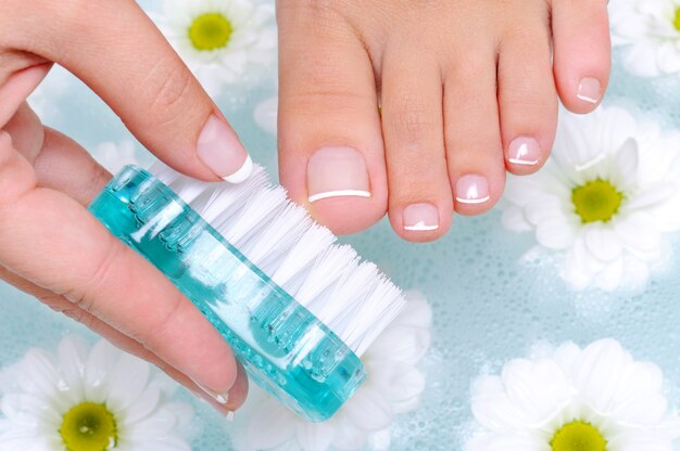 Mulher lava e limpa as unhas dos pés na água