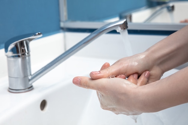 Mulher lavando as mãos cuidadosamente com sabonete e desinfetante, close-up. Prevenção da propagação do vírus da pneumonia, proteção contra a pandemia de coronavírus. Higiene, higiene, limpeza, desinfecção. Segurança.
