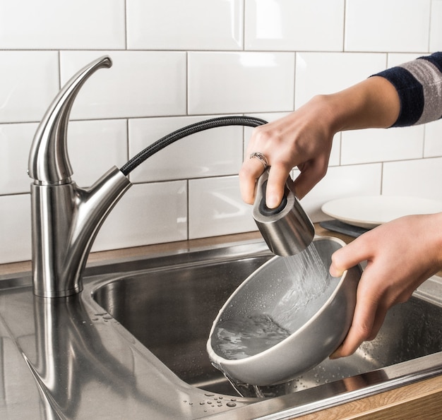 Mulher lavando pratos na cozinha