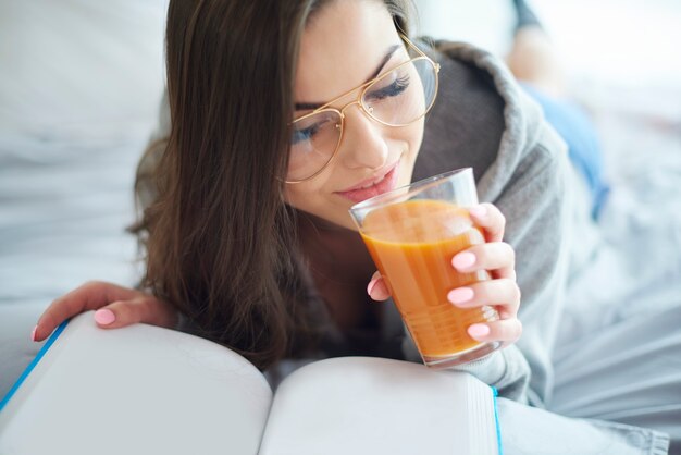 Mulher lendo livro e bebendo suco