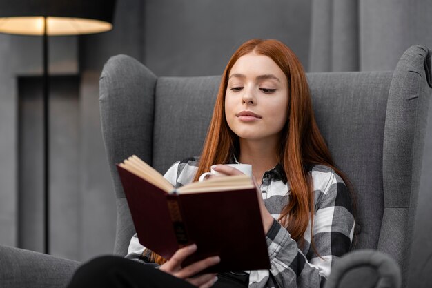 Mulher lendo um livro dentro de casa