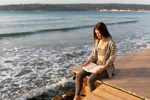 Foto grátis mulher lendo um livro na praia