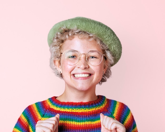 Mulher lésbica feliz com suéter arco-íris em uma maquete rosa na parede