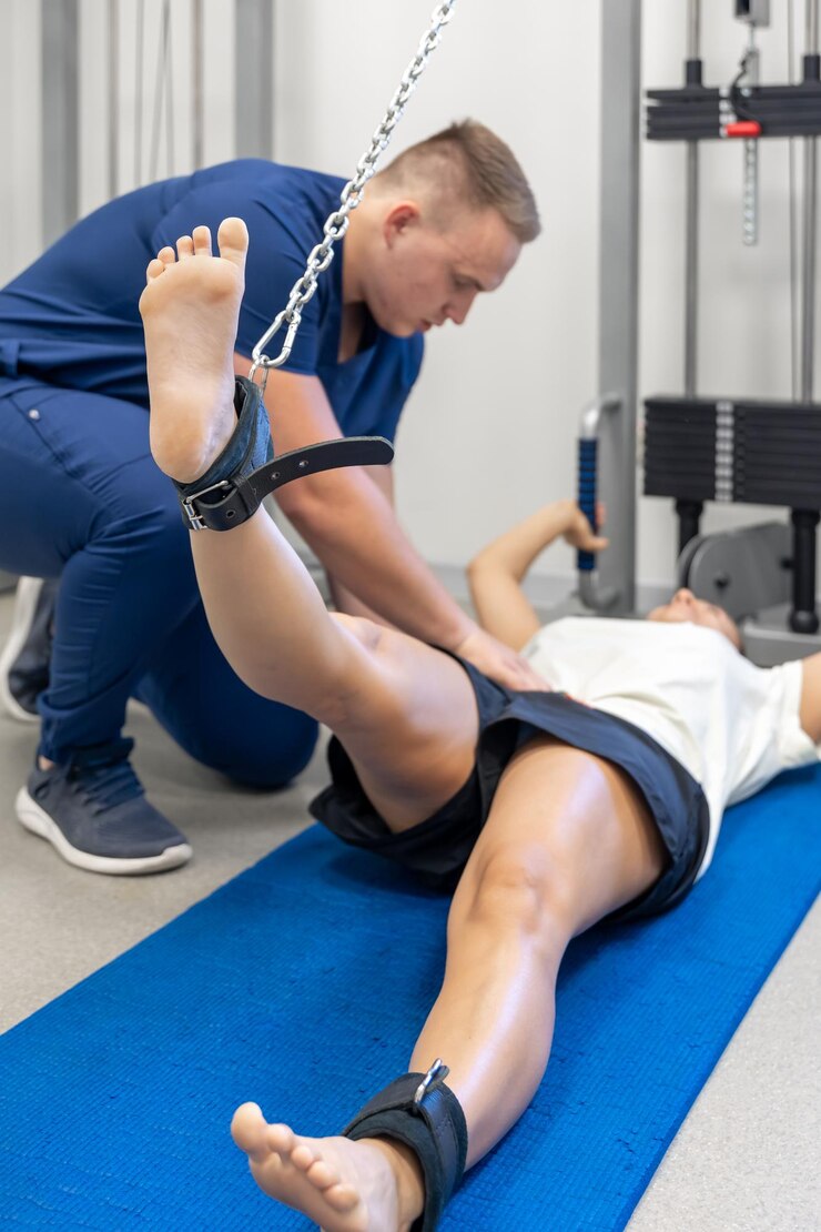 Foto grátis mulher levanta as pernas terapeuta de exercícios ajudando com distúrbios mecânicos