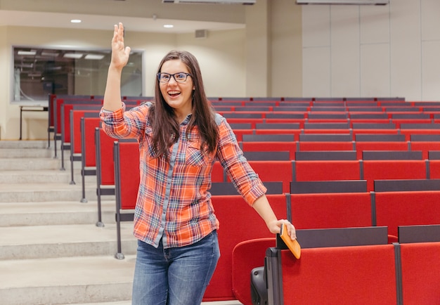 Mulher levantando mão no anfiteatro da universidade