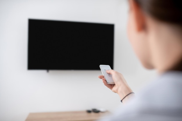 Foto grátis mulher ligando a tv de plasma montada na parede