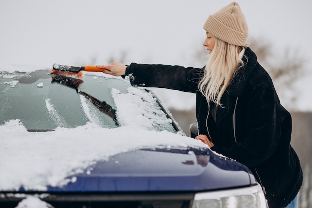 Mulher limpando a neve da janela do carro