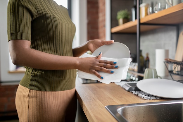 Mulher limpando prato na cozinha