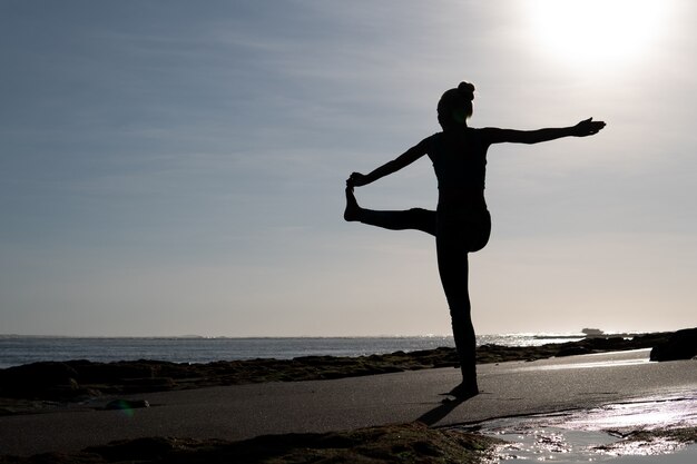 Mulher linda fazendo ioga na praia