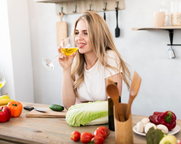 Mulher loira bebendo de um copo na cozinha