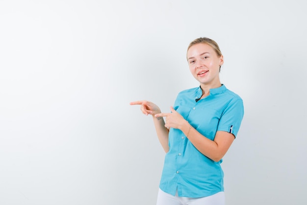 Foto grátis mulher loira com blusa azul apontando para a esquerda e parecendo alegre