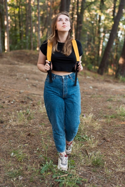 Mulher loira com mochila na floresta