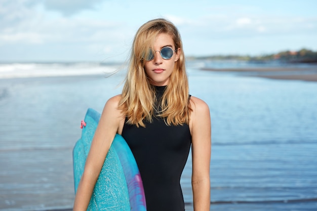 Mulher loira com prancha de surf na praia
