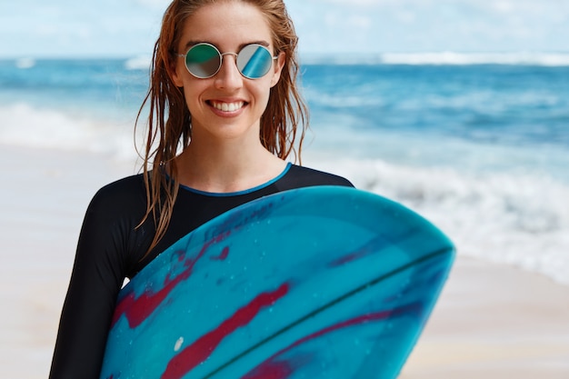 Mulher loira com prancha de surf na praia