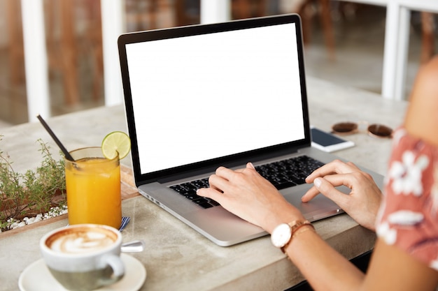 Mulher loira com vestido floral em um café com laptop