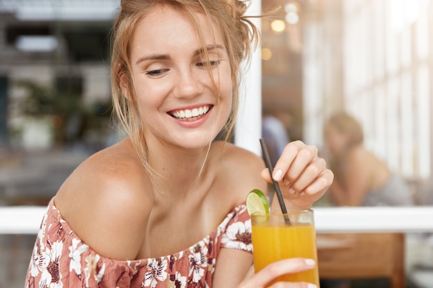 Mulher loira com vestido floral em um café