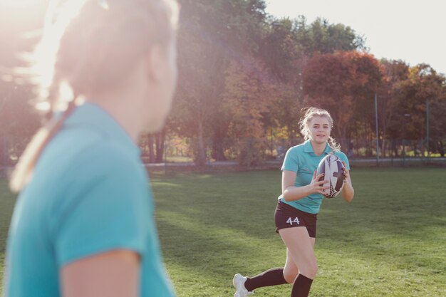 Mulher loira correndo com uma bola de rugby