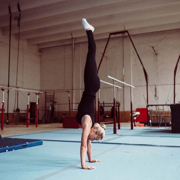 Foto grátis mulher loira de lado treinando para as olimpíadas de ginástica