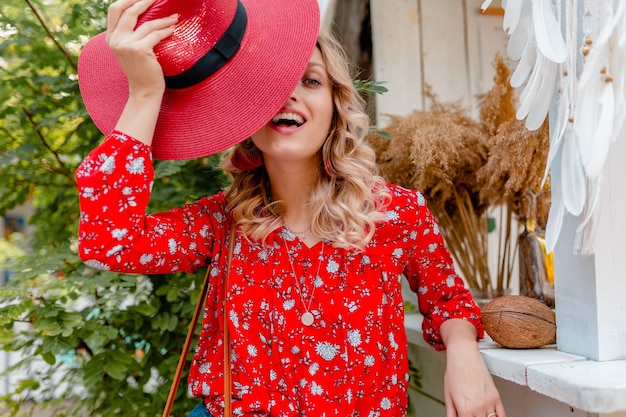 Mulher loira elegante muito atraente e sorridente com chapéu vermelho palha e blusa moda verão café