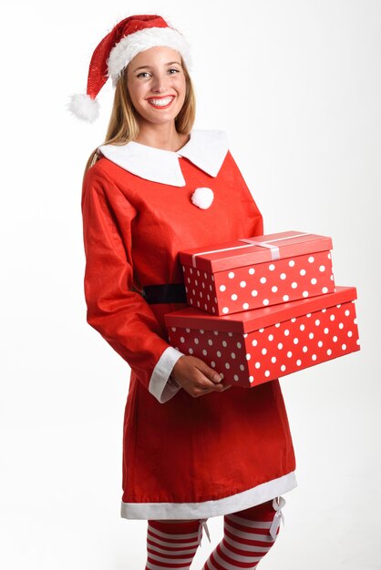 Mulher loira em roupas de Papai Noel sorrindo com caixas de presente.