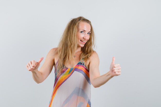 Mulher loira mostrando dois polegares para cima em um vestido de verão e parecendo alegre
