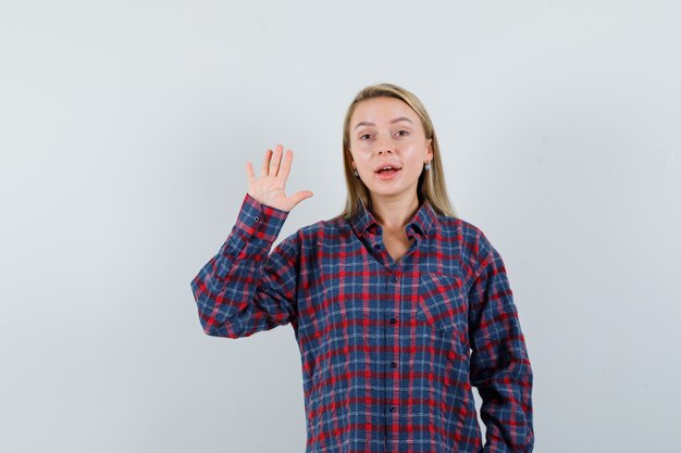 Mulher loira mostrando o sinal de stop na camisa e olhando otimista, vista frontal.