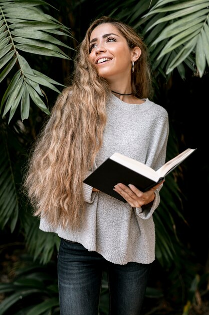 Mulher loira posando do lado de fora, segurando um livro