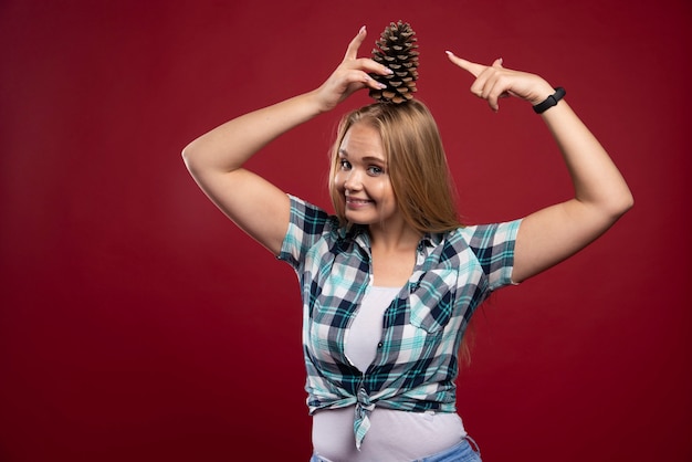 Foto grátis mulher loira segura o cone do carvalho na cabeça e se sente positiva.