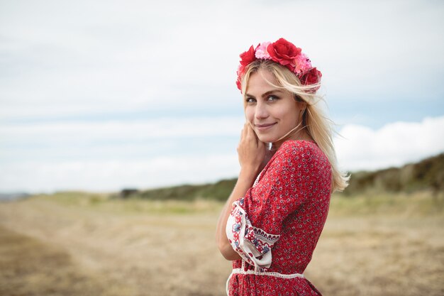 Mulher loira, vestindo uma tiara de flor em pé no campo