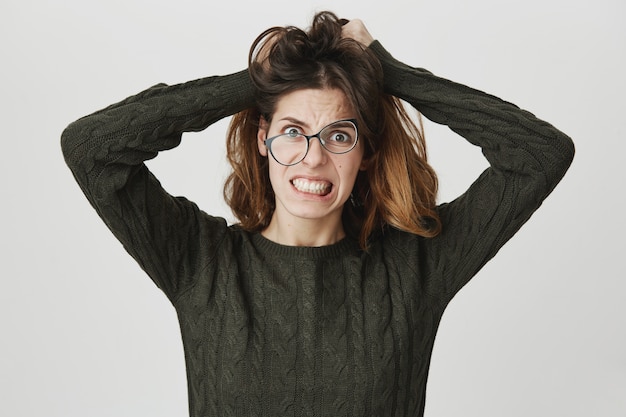 Foto grátis mulher louca desesperada despenteia o cabelo, usa óculos tortos, cerra os dentes em desespero e raiva
