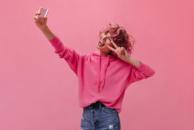 Mulher louca e ativa com cabelo rosa fazendo selfie isolado