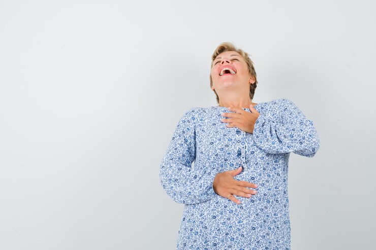 Foto grátis mulher madura com camisa, segurando a mão no peito enquanto ri