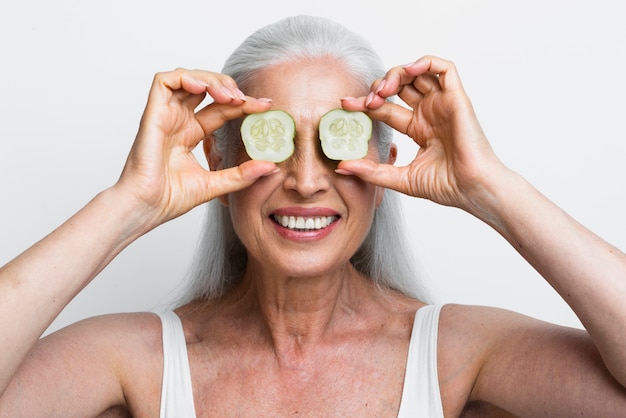 Mulher madura com fatias de pepino nos olhos