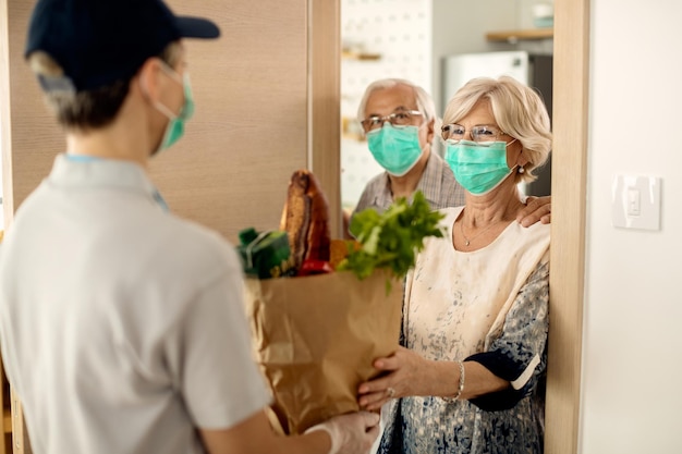 Mulher madura feliz e seu marido recebendo mantimentos em casa durante a epidemia de coronavírus
