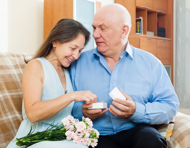 Mulher madura feliz que olha a jóia