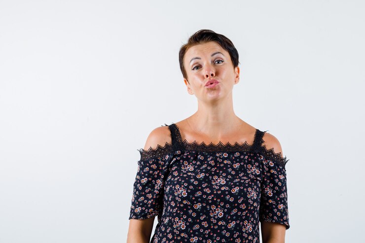 Foto grátis mulher madura mandando beijos para a câmera em blusa floral, saia preta e olhando alegre, vista frontal.