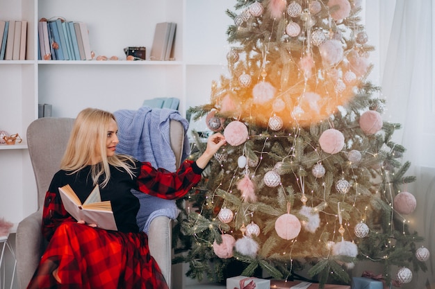 Mulher madura, sentado na cadeira pela árvore de Natal